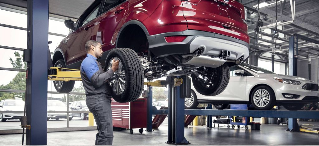 Ford service technician performing tire maintenance.  Read this article for vehicle service appointment hints.